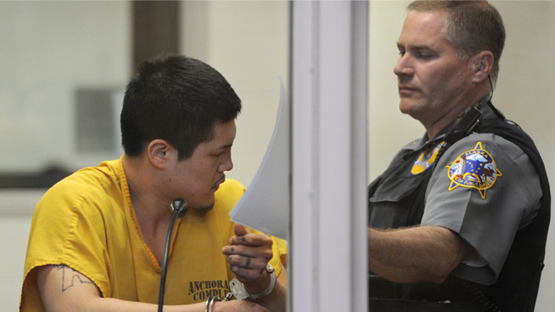 May 26, 2013: An officer in the Anchorage jail court removes the paperwork that Jerry Andrew Active was using to shield his face during his arraigned on charges of murder and sexual assault of a minor in Anchorage, Alaska.