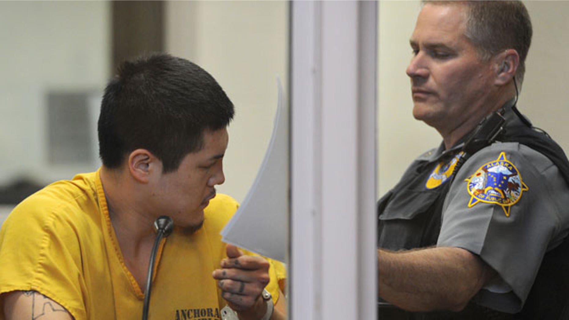 May 26, 2013: An officer in the Anchorage jail court removes the paperwork that Jerry Andrew Active was using to shield his face during his arraigned on charges of murder and sexual assault of a minor.