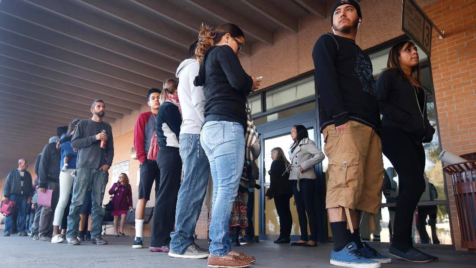 FILE - This Dec. 22, 2014 file photo a line stretches outside an a Arizona Department of Transportation Motor Vehicle Division office, begin pursuing Arizona driver's licenses. Only a small number of young immigrants who qualify for Arizona driver's licenses after a judge overturned a state ban have actually obtained licenses. Immigrant advocates say not enough people know they qualify. (AP Photo/Ross D. Franklin,File)