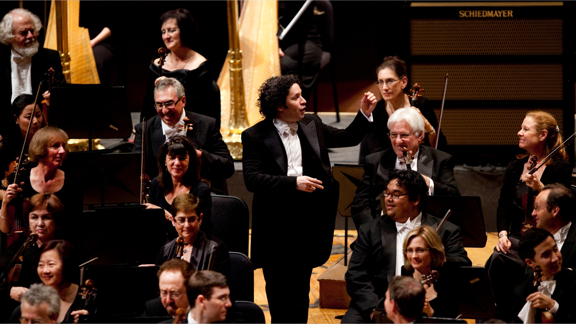 Venezuela's conductor Gustavo Dudamel walks between musicians after directing a concert with the Los Angeles Philharmonic at Teresa Carreno Theater in Caracas, Venezuela, Wednesday Feb. 15, 2012. Star conductor Gustavo Dudamel is thrilling fans in Venezuela as he performs with the Los Angeles Philharmonic for the first time in his homeland, fresh off winning a Grammy. (AP Photo/Ariana Cubillos)