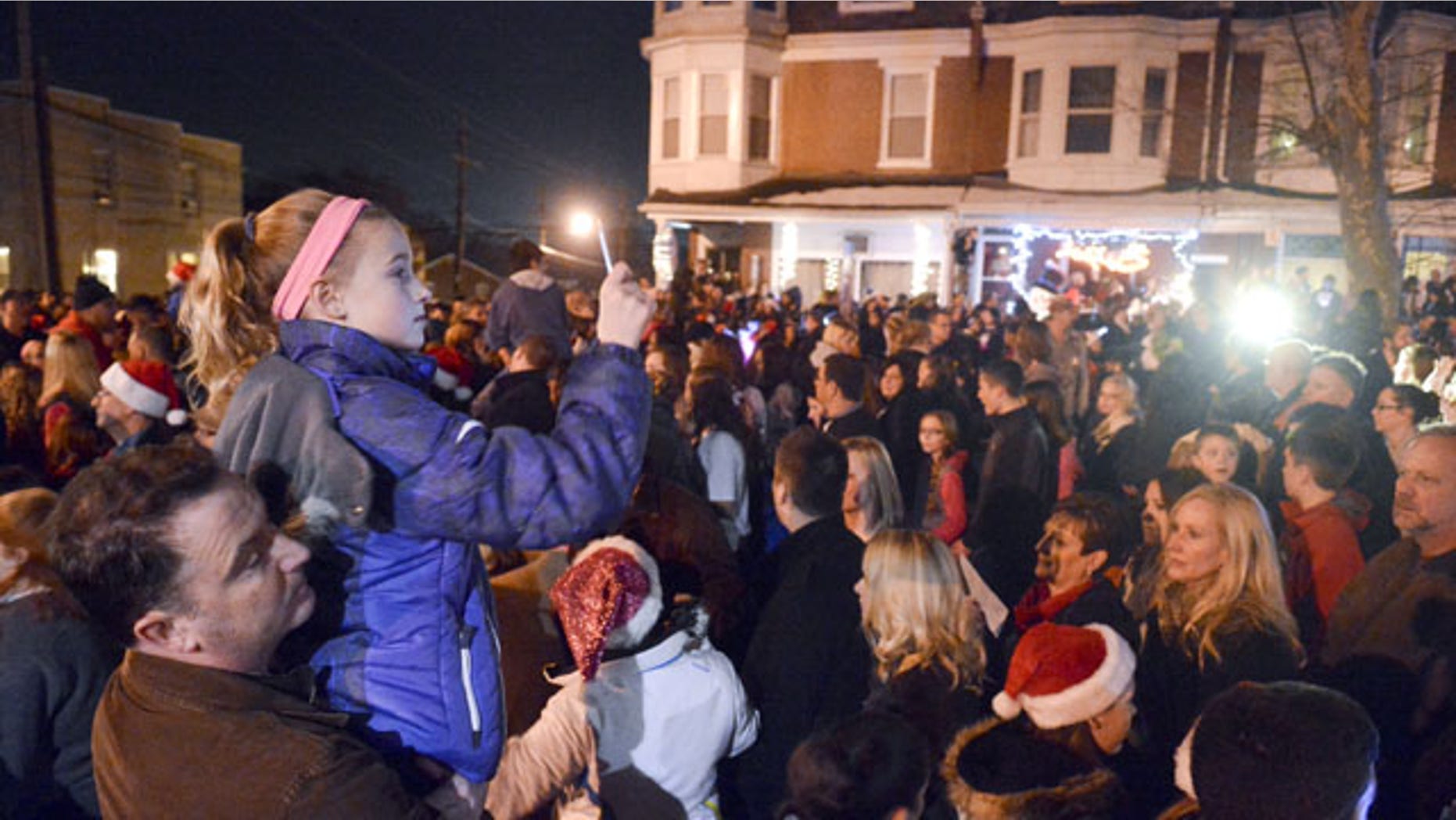 December 21, 2013:Mike Simmons holds his daughter Gracie Simmons, 11, both of Wyomissing, while Gracie shoots video of the caroling in West Reading, Pa., where thousands of people came out to sing Christmas carols in front of the home of Delaney "Laney" Brown, 8, who is terminally ill with a rare form of leukemia. (AP Photo/Reading Eagle, Ben Hasty)