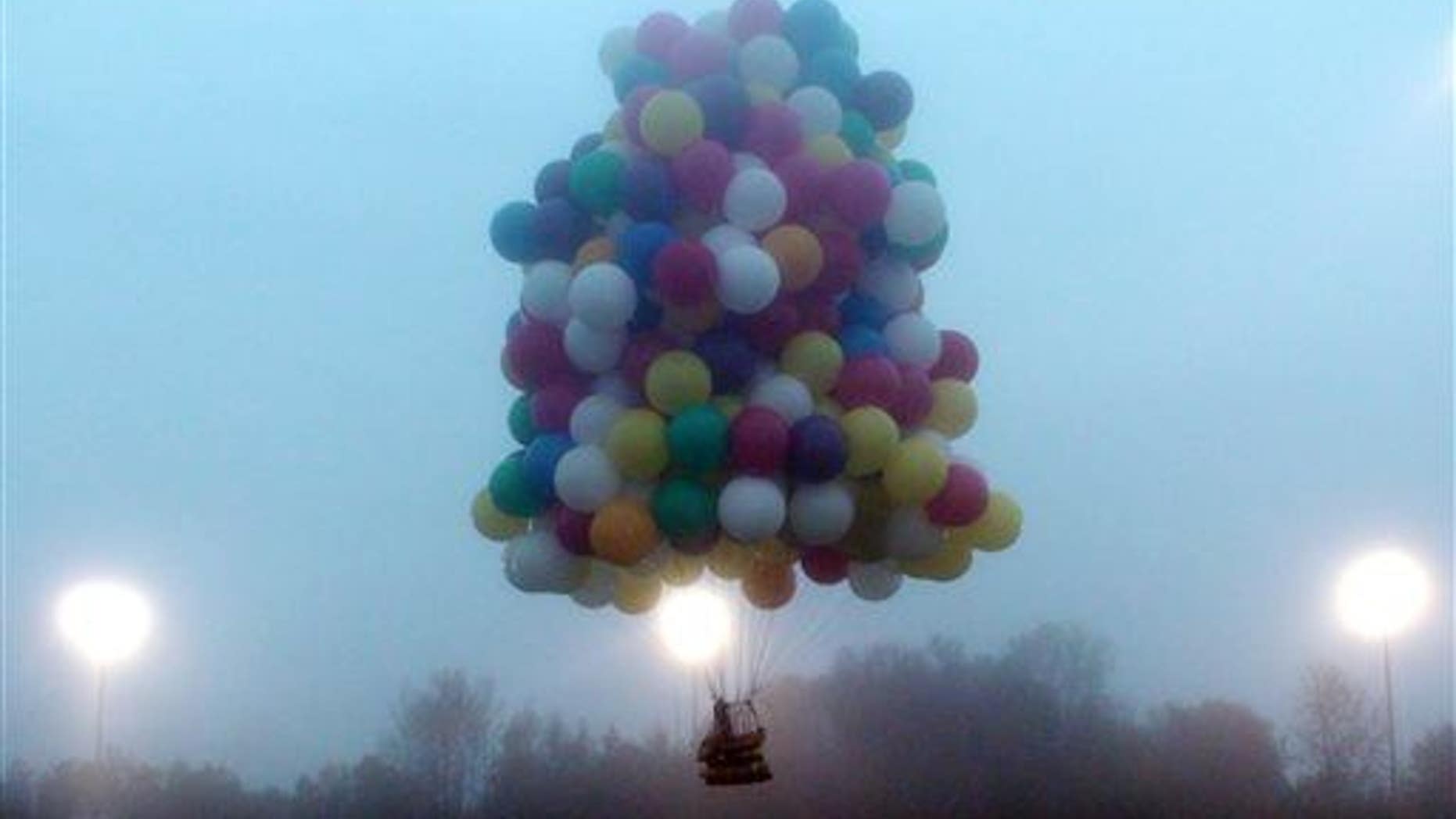 In this photo provided by Mark McBreairty, a balloon cluster carrying Jonathan Trappe lifts off from Caribou, Maine, Thursday, Sept. 12, 2013.