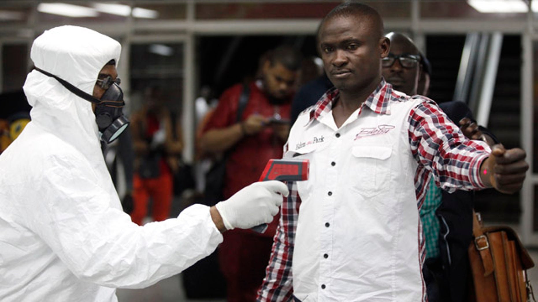 FILE - In this Aug. 6, 2014 file photo, a Nigerian port health official uses a thermometer on a worker at the arrivals hall of Murtala Muhammed International Airport in Lagos. As the Ebola outbreak in West Africa grows, airlines around the globe are closely monitoring the situation but have yet to make any drastic changes. (AP Photo/Sunday Alamba, File)