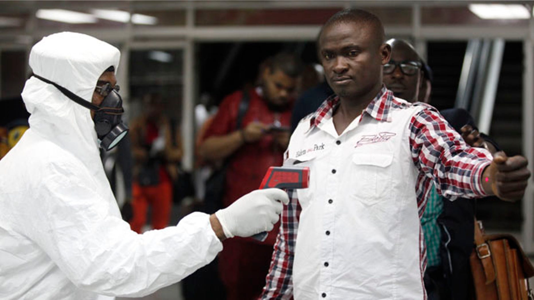 In this Aug. 6, 2014 file photo, a Nigerian port health official uses a thermometer on a worker at the arrivals hall of Murtala Muhammed International Airport in Lagos, Nigeria.