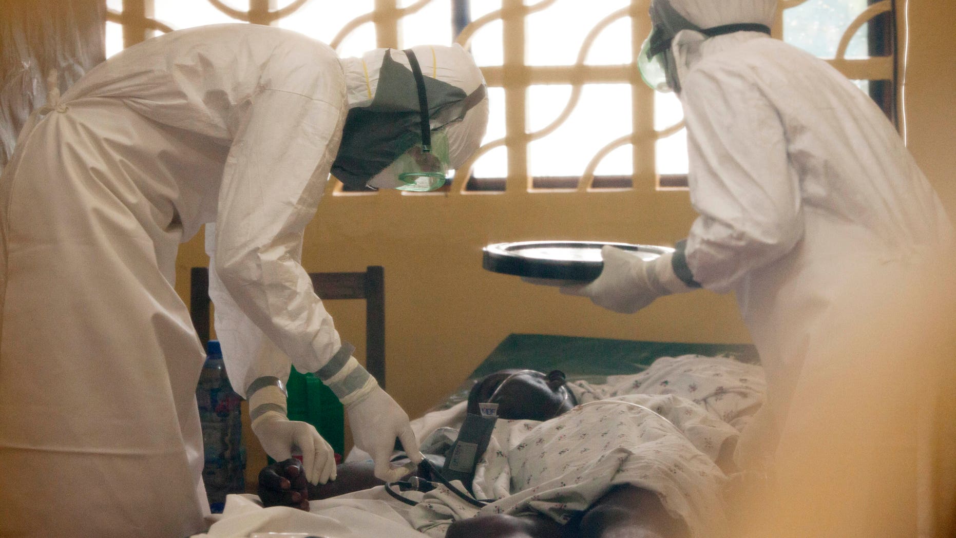 In this 2014 photo provided by the Samaritan's Purse aid organization, Dr. Kent Brantly, left, treats an Ebola patient at the Samaritan's Purse Ebola Case Management Center in Monrovia, Liberia. On Saturday, July 26, 2014, the North Carolina-based aid organization said Brantly tested positive for the disease and was being treated at a hospital in Monrovia. (AP Photo/Samaritan's Purse)