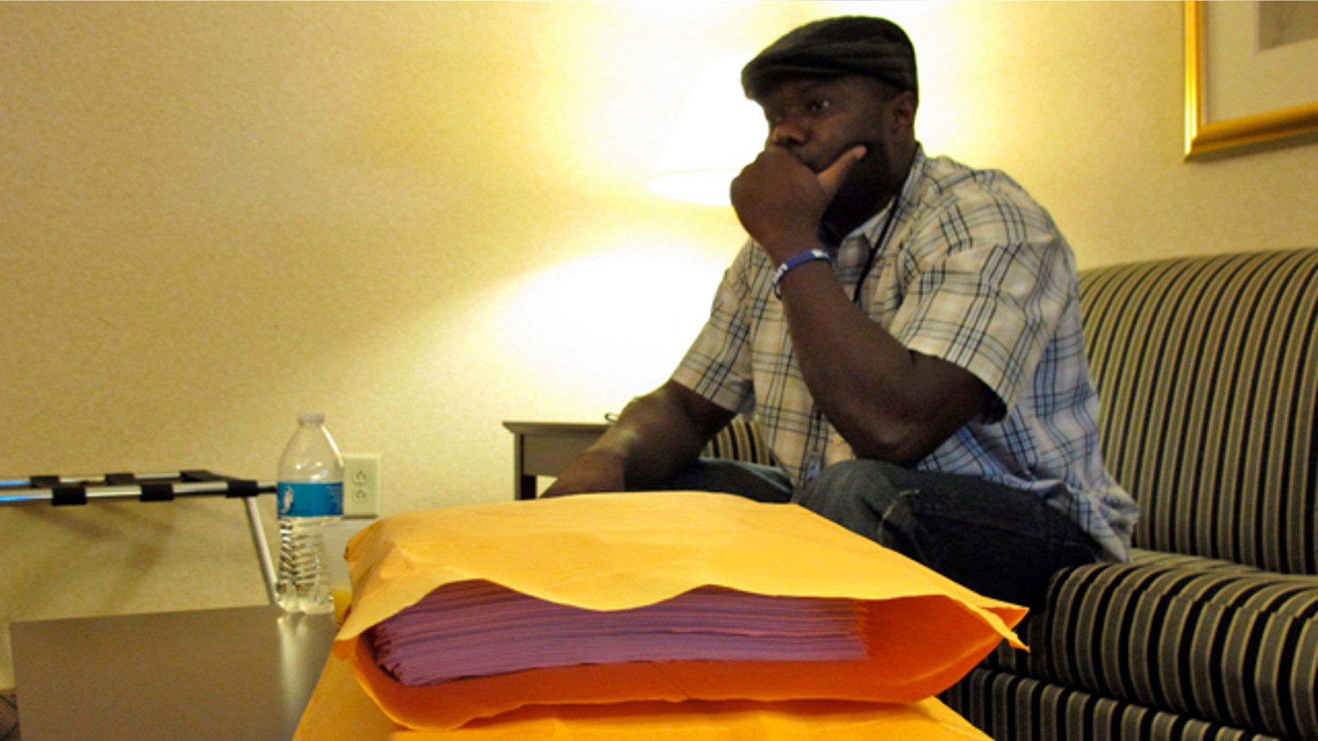 October 10, 2014: Josephus Weeks, nephew of Ebola patient Thomas Eric Duncan who died earlier this week in Dallas, sits behind a stack of medical documents in a hotel room in Kannapolis, N.C. (AP Photo/Allen G. Breed)