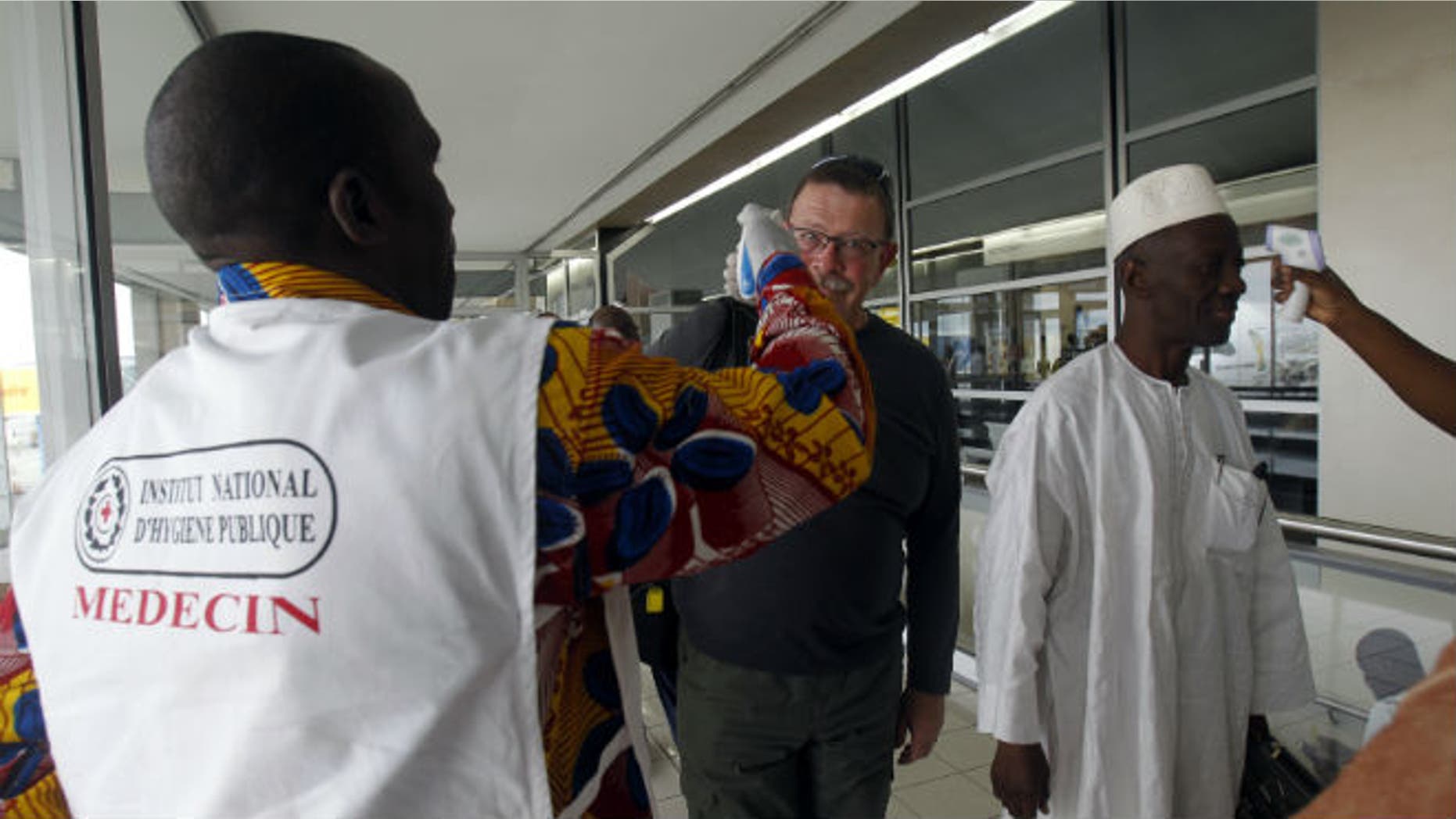 Health workers take passengers' temperatures infrared digital laser thermometers at the Felix Houphouet Boigny international airport in Abidjan August 13, 2014. REUTERS/Luc Gnago