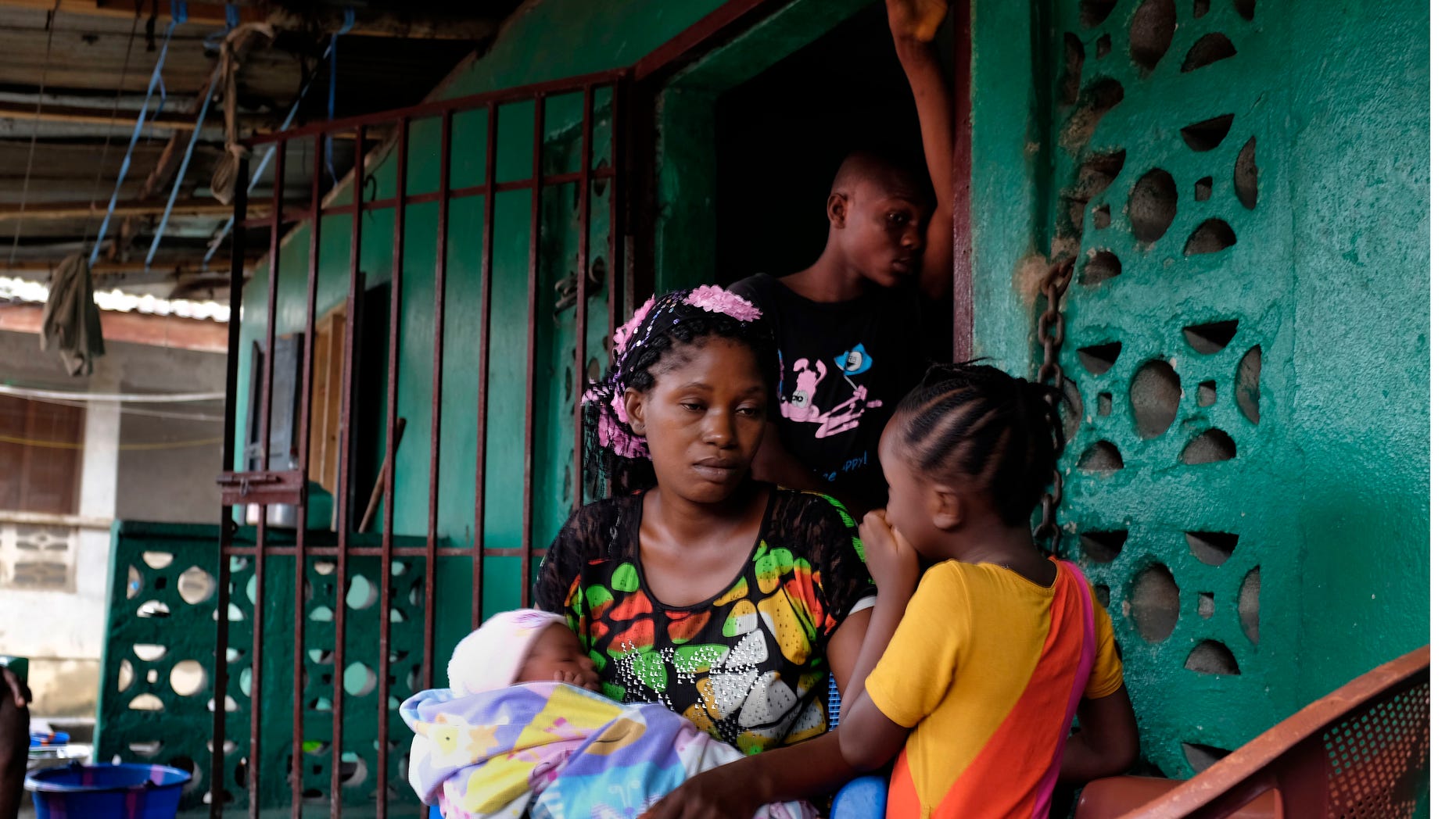 In this picture taken Sunday, Sept. 28, 2014, Finda Saah, 28, holds six-week-old Prosper Junior, as 5 year old Alice and 13-year old son Augustin look on, at their St Paul Bridge home in Monrovia, Liberia. (AP Photo/Jerome Delay)