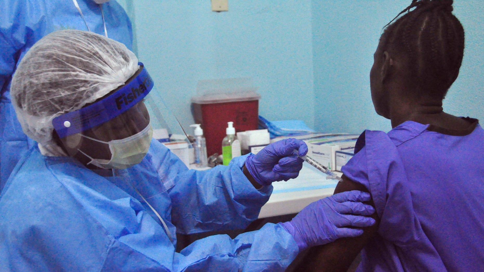 A woman is injected by a health care worker, left, as she takes part in an Ebola virus vaccine trial, at one of the largest hospital's Redemption hospital in Monrovia, Liberia, Monday, Feb. 2, 2015. (AP Photo/ Abbas Dulleh)