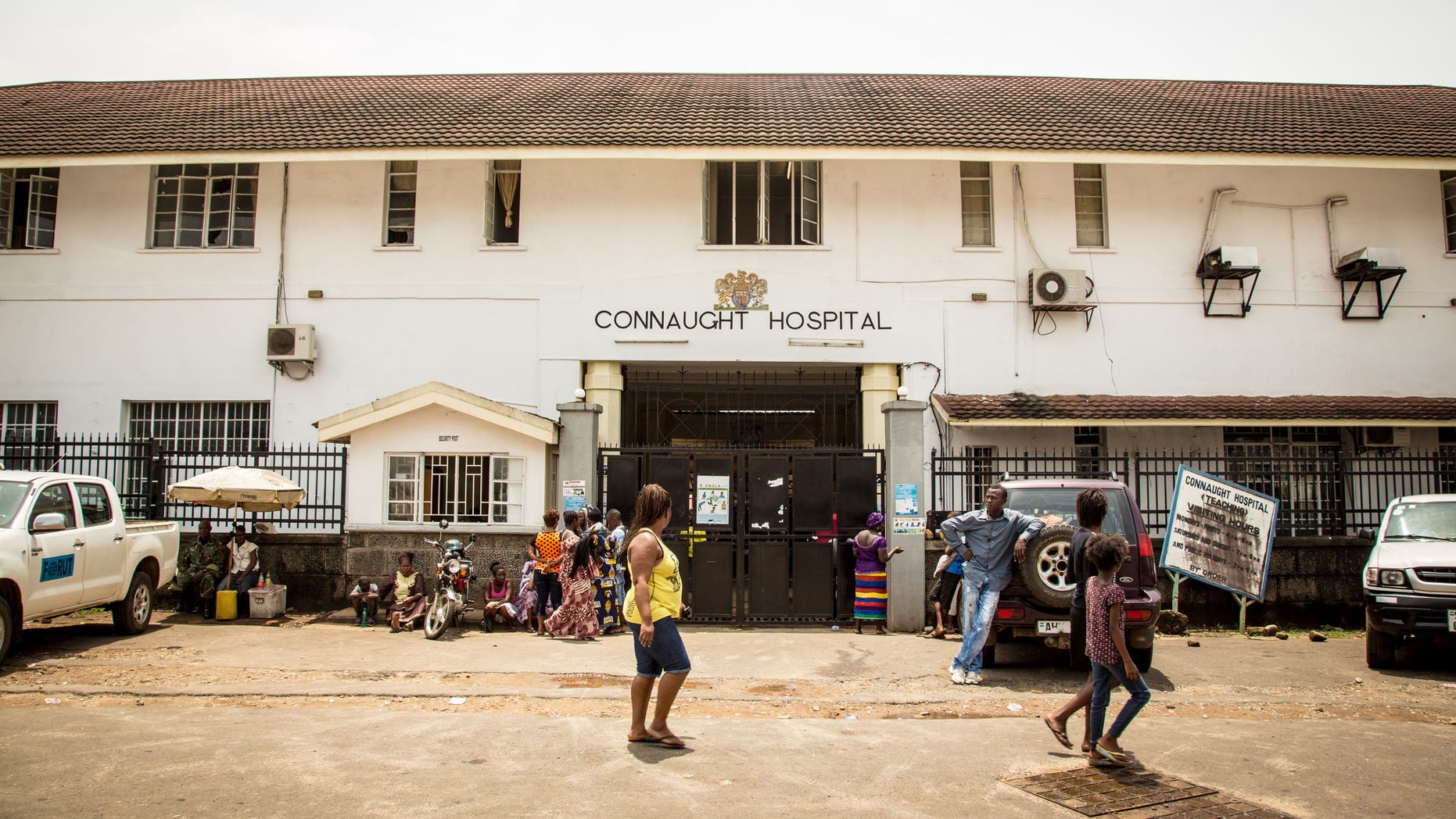 In this photo taken on Sunday, Sept. 14, 2014, people walk past the Connaught Hospital that is used for treating people suffering from the Ebola virus in Freetown, Sierra Leone. (AP Photo/ Michael Duff)