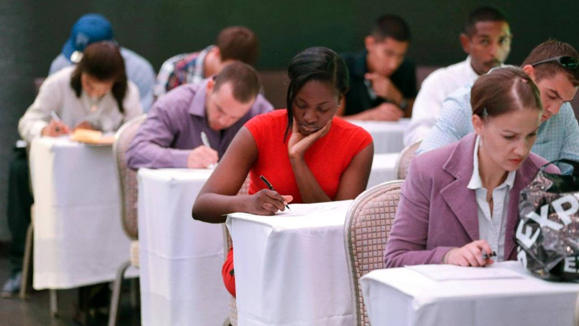 In this Monday, Oct. 6, 2014 photo, job seekers fill out forms before being interviewed during a job fair at Fontainebleau Miami Beach in Miami Beach, Fla. The recovery of the U.S. job market has reached a new milestone on its road to full health: For the first time since the Great Recession ended 5½ years ago, America’s unemployed are now as likely to be hired as to stop looking for a job. (AP Photo/Wilfredo Lee)