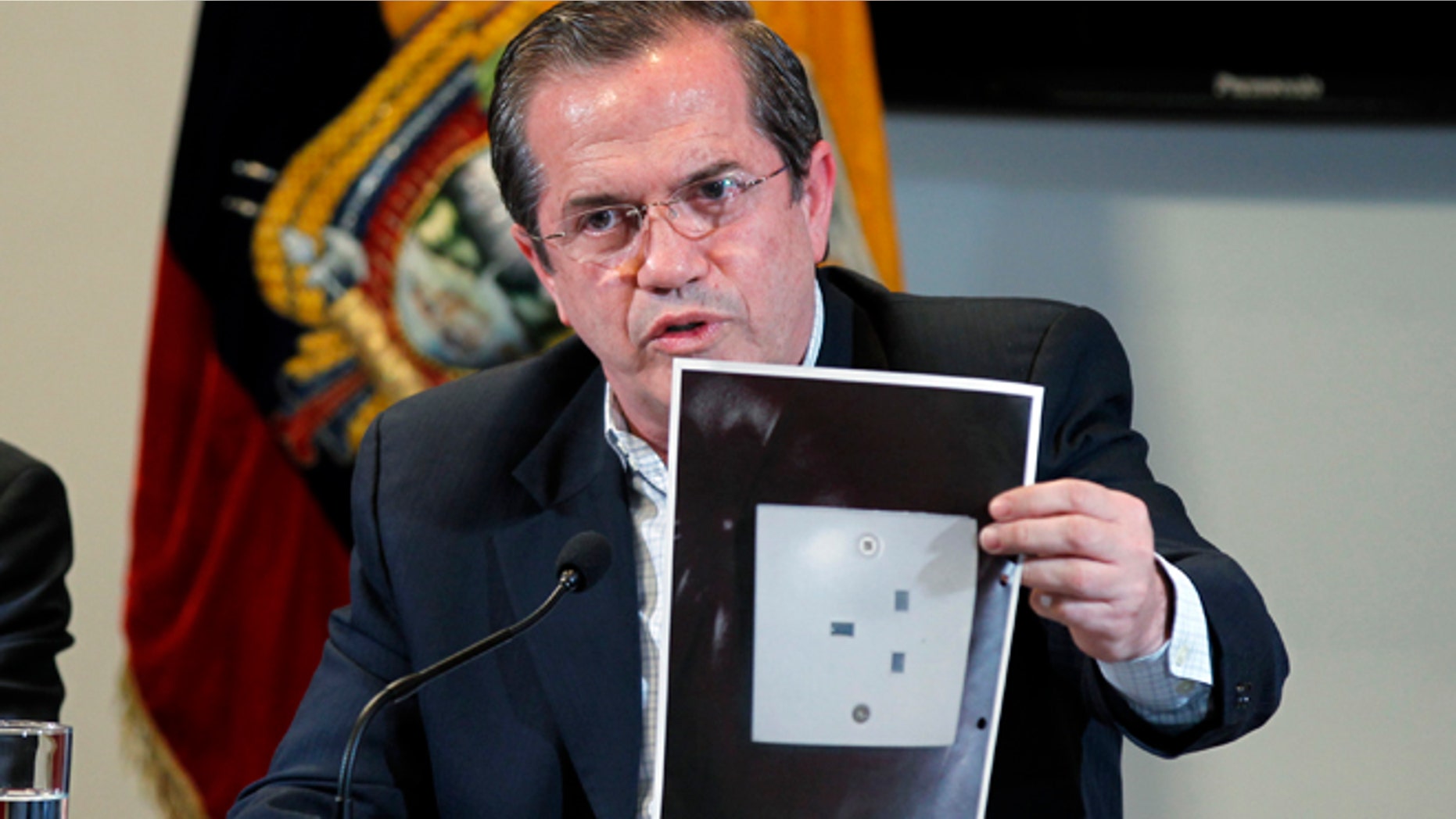 Ecuador's Foreign Minister Ricardo Patino holds up a photograph of what he says is the electric socket at his country's embassy in London where a hidden microphone was found, during a press conference in London in Quito, Ecuador, Wednesday, July 3, 2013. Patino said that two weeks ago a hidden microphone was found where Wikileaks founder and publisher Julian Assange is holed up. "We want to find out with precision what the origin of the apparatus is." (AP Photo/Dolores Ochoa)