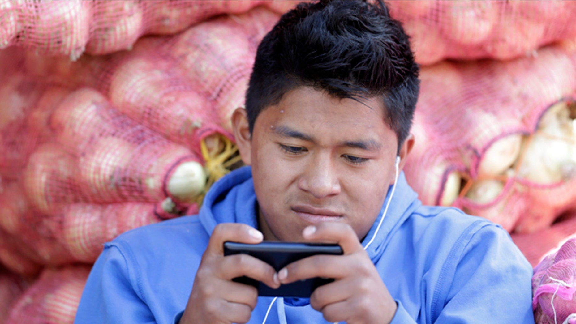 In this Aug. 24, 2014, photo, a young man texts a message on his mobile phone while working at the Mayorista Market in Quito, Ecuador. Ecuador's Central Bank is getting ready to use electronic currency in which consumers will initially be able to use it to make and receive payments using their cellphones. Ecuador is heralding its plans to create the worlds first government-issued digital currency, which some analysts believe could ultimately replace the countrys existing currency, the U.S. dollar, which the government cannot control. (AP Photo/Dolores Ochoa)