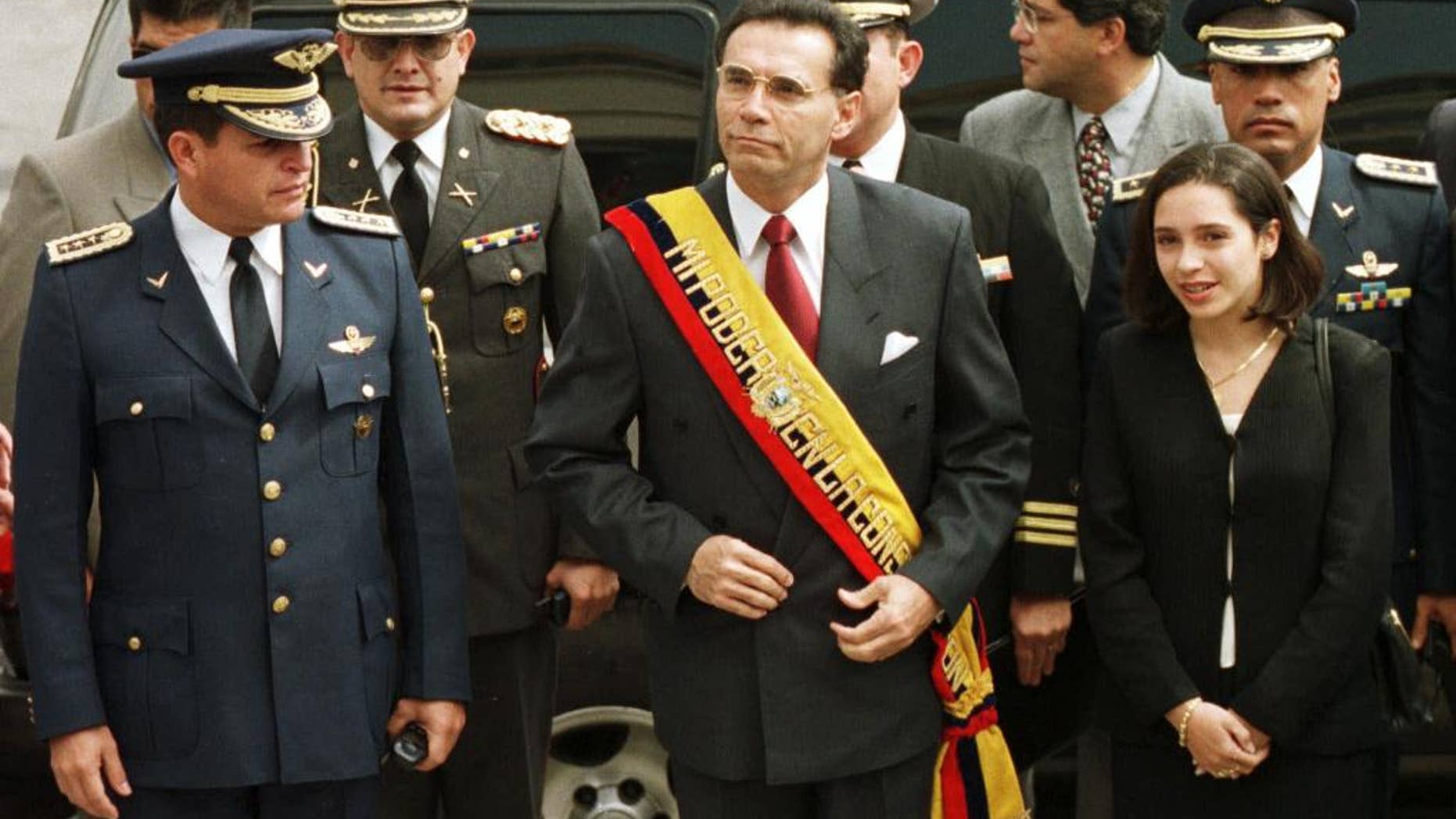 FILE - In this Jan. 15, 2000 file photo, Ecuador's President Jamil Mahuad, center, his daughter Paola Mahuad, right, and military officials arrive to Congress in Quito, Ecuador. Ecuadorean authorities announced on Tuesday, May 27, 2014 via Twitter that an arrest warrant has been issued for former President Jamil Mahuad for allegedly misappropriating public funds during the country's late 1990s banking crisis. Mahuad fled a 2000 coup and settled in the United States. (AP Photo/Silvia Izquierdo, File)