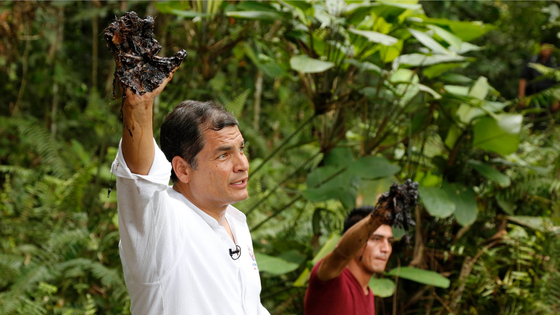 FILE - In this Sept. 17, 2013, file photo, Ecuador's President Rafael Correa shows his oil covered glove at the site of the Aguarico 4 oil field in Ecuador. President Correa explained on Tuesday, Aug. 25, 2015, that the country is now producing oil at a loss. (AP Photo/Dolores Ochoa, File)