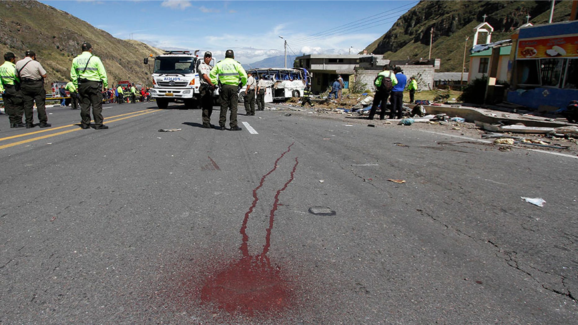 Police officers block traffic at the site where a Colombian-registered bus traveling to Quito crashed in Pifo, Ecuador.