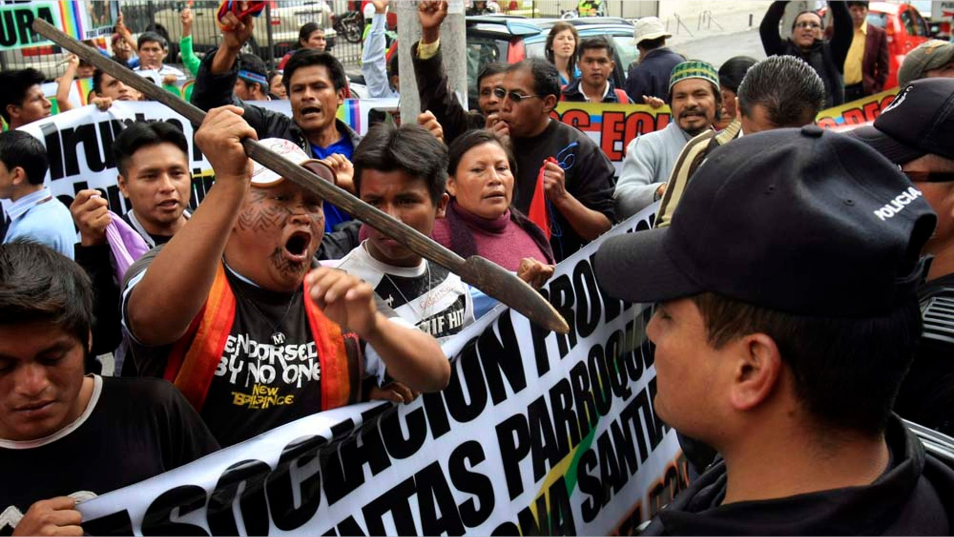 Shuar Indigenous men, one brandishing a lance, protest in front of police standing guard outside a court where former Indigenous leader Pepe Acacho attends a hearing in Quito, Ecuador, Monday Feb. 7, 2011. Acacho was detained Feb. 1 in Macas, Ecuador's southern Amazon region, along with Indigenous leaders Pedro Mashiant and Fidel Kaniras, all three accused of sabotage and terrorism involving a death for their alleged involvement during the Sept. 2009 protests where Bosco Wisuma, a teacher from the Shuar indigenous nationality, was killed. (AP Photo/Dolores Ochoa)