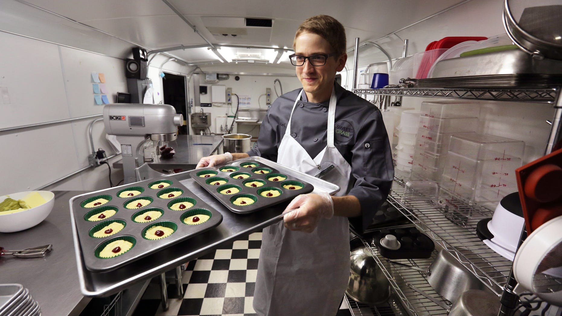 FILE - In this June 19, 2014, file photo, chef Alex Tretter carries a tray of cannabis-infused peanut butter and jelly cups to the oven for baking at Sweet Grass Kitchen, a well-established Denver-based gourmet marijuana edibles bakery which sells its confections to retail outlets throughout the state. Colorado marijuana regulators have drafted an emergency rule aimed at making it easier for new marijuana users to tell how much pot they are eating. (AP Photo/Brennan Linsley, File)