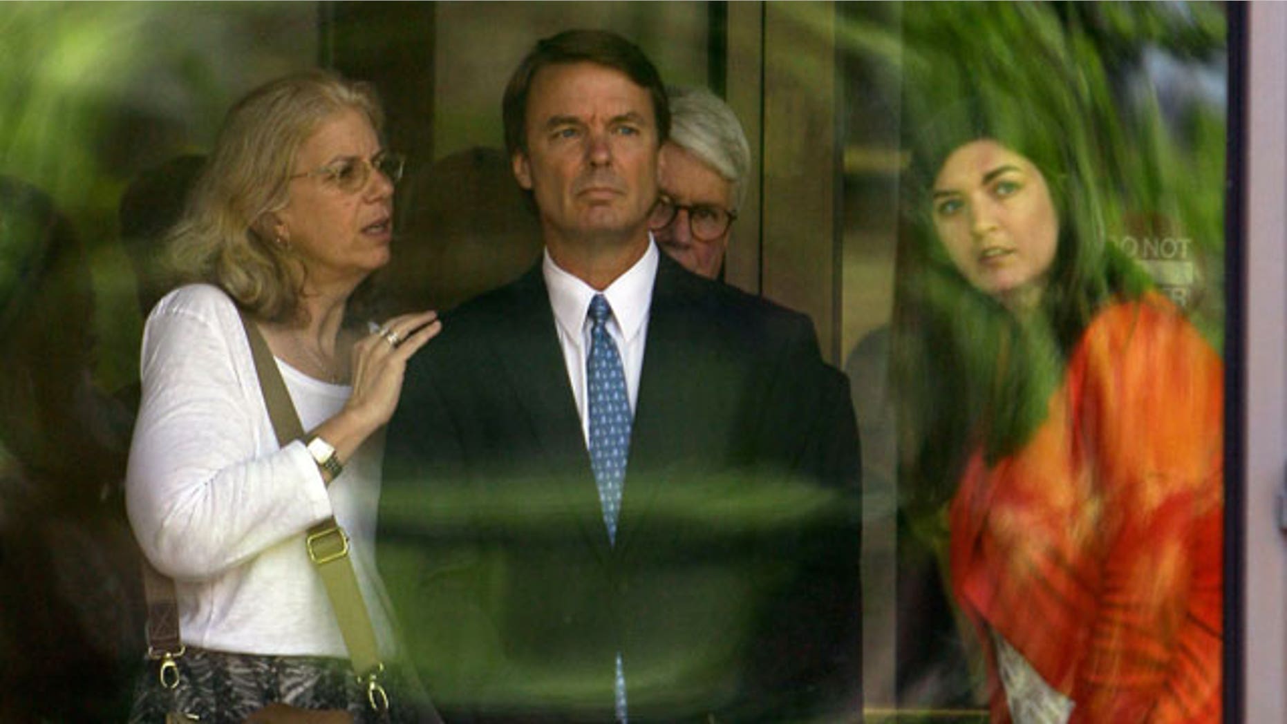 Former presidential candidate John Edwards, center, is seen with his daughter Cate, right, as they peer out of the federal building following a court appearance in Winston-Salem, N.C., Friday, June 3, 2011. (AP)