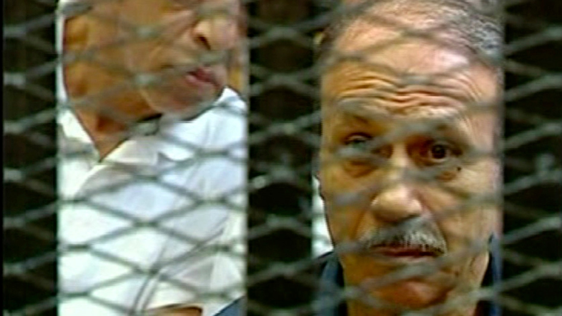 Egyptian Interior Minister Habib el-Adly, right, in a cage of mesh and iron bars during his trial in a Cairo courtroom Thursday Aug. 4, 2011.