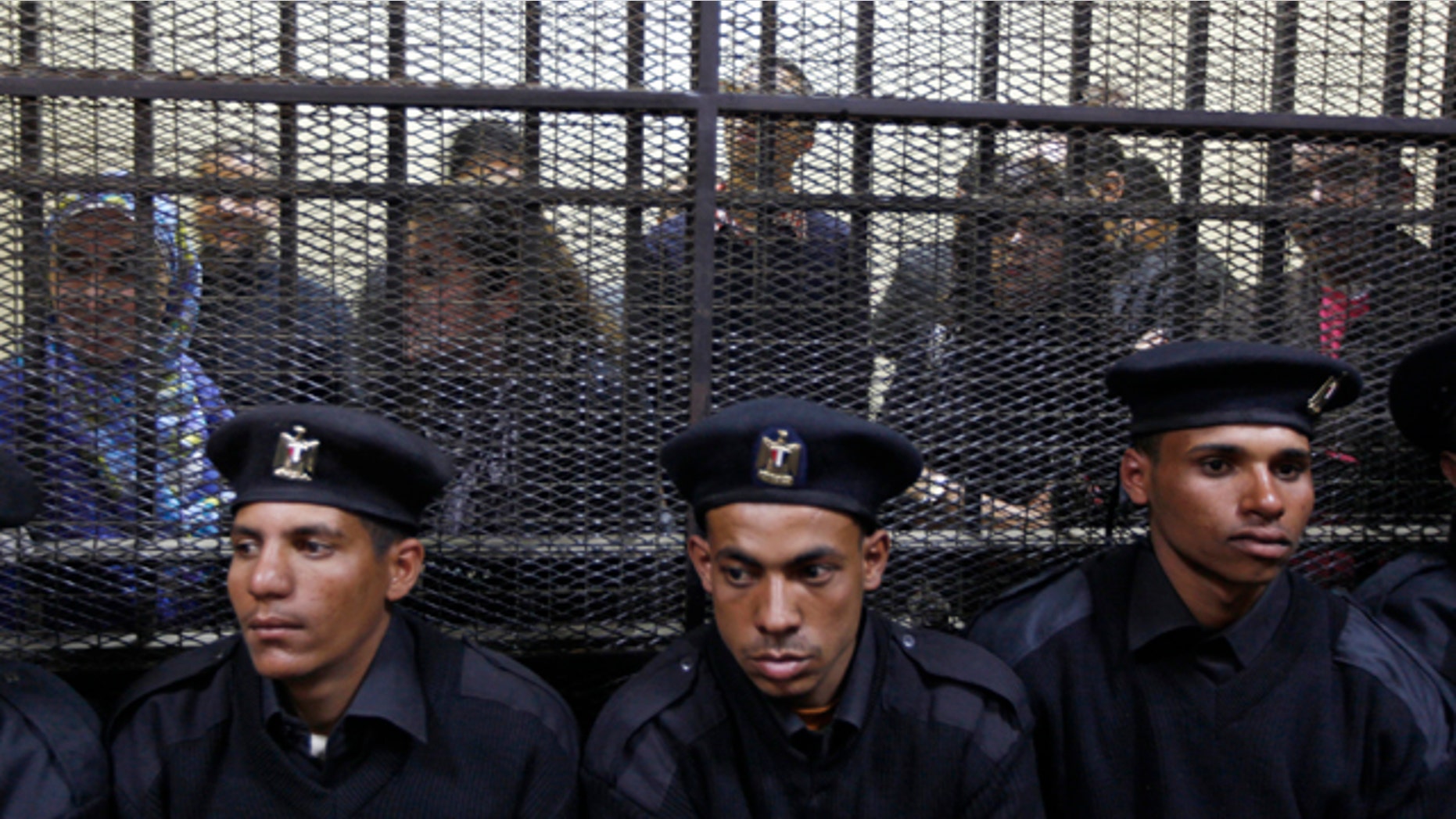 Feb. 26: Egyptian policemen sit in front of Egyptian employees of several pro-democracy groups charged with using foreign funds to foment unrest during their trial in Cairo, Egypt.