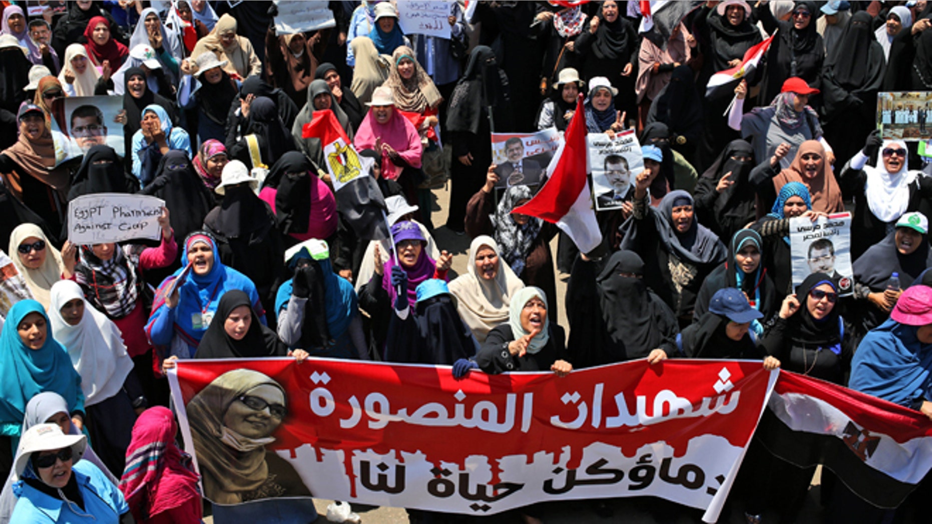 July 21, 2013: Supporters of ousted Egyptian President Mohammed Morsi carry a banner with Arabic words that reads, "Martyrs of Mansoura, your bloods is life for us," depicting a woman who was killed during a recent protest, as they attend a demonstration in front of the National Council for Human Right building in Cairo, Egypt.