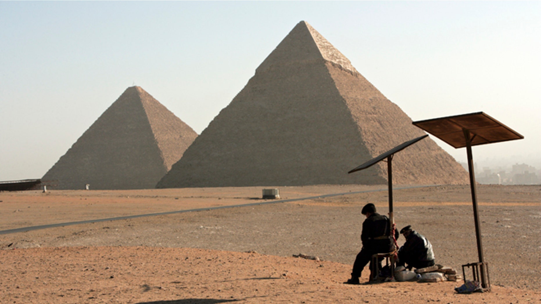 CAIRO, EGYPT - FEBRUARY 9. Two Egyptian Tourist Police Officers guard the area of the Great Pyramides Chephren and Mycerinus seen on the background on February 9, 2006 in Giza, Cairo, Egypt. (Photo by Marco Di Lauro/Getty Images)