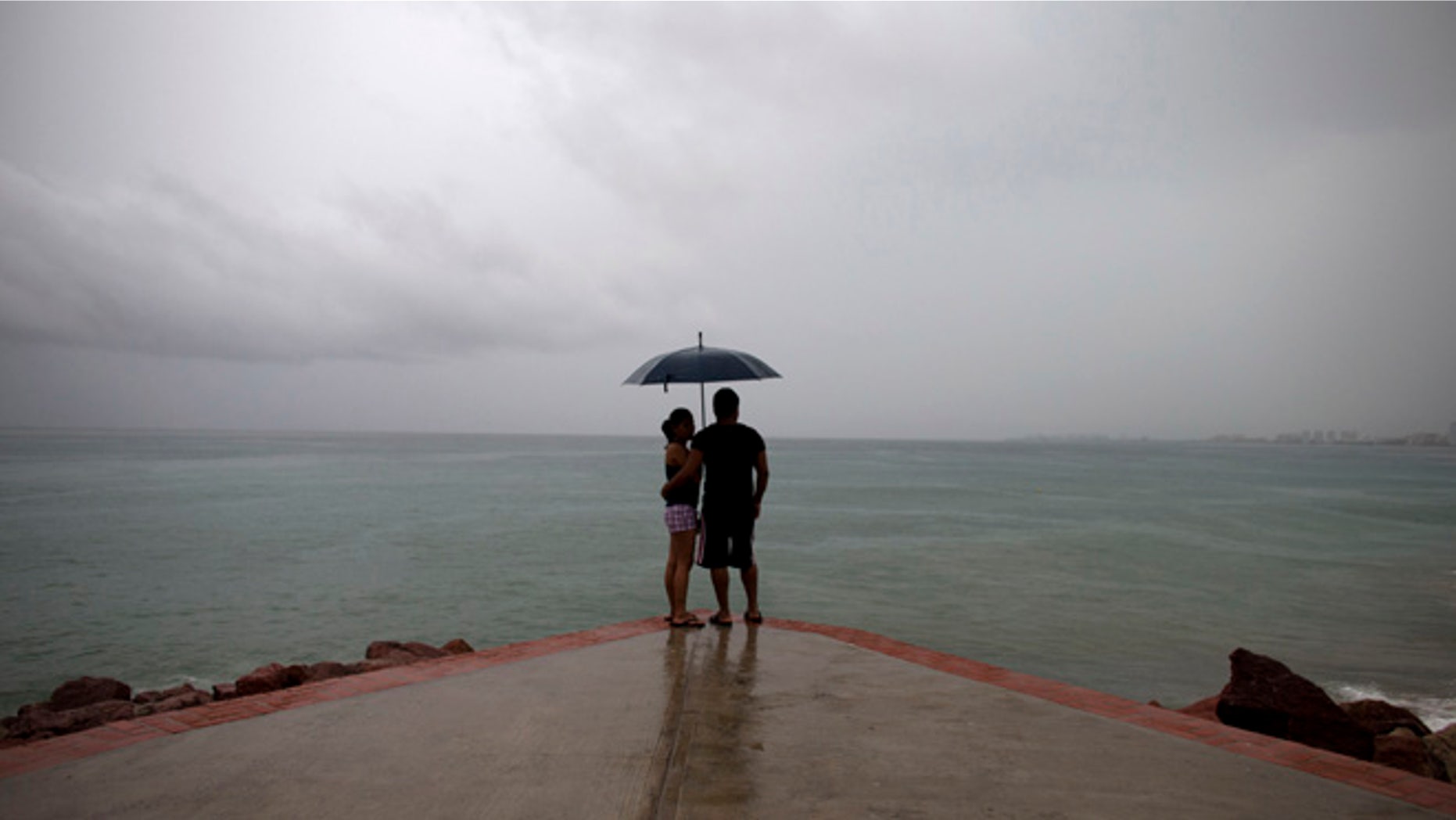FILE - In this Friday, Oct. 23, 2015, file photo, a couple looks out to sea as rainfall increases with the approach of Hurricane Patricia in Puerto Vallarta, Mexico. Mexico weathered a record eastern Pacific hurricane season with almost no deaths and relatively little damage, given the intensity of this year's storms. According to the U.S. National Oceanic and Atmospheric Administration's 2015 hurricane season report released Tuesday, Dec. 1, 2015, Patricia was "the strongest hurricane on record in the Western Hemisphere" just before it struck a sparsely populated stretch of Mexico's Pacific coast. (AP Photo/Rebecca Blackwell, File)