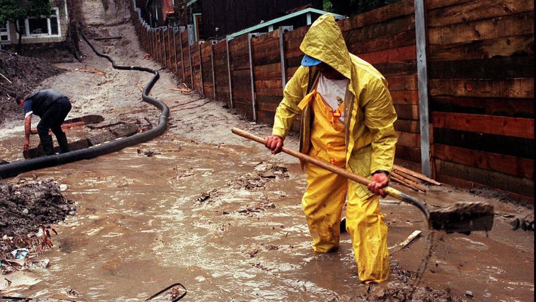 FILE - In this Wednesday, March 25, 1998 file photo, Enrique Lagunas digs a trench to redirect water toward a street in Laguna Beach, Calif. after heavy rains from an El Nino storm hit Southern California. On Thursday, March 6, 2014, the U.S. National Oceanic Atmospheric and Administration announced their prediction of an El Nino warming of the central Pacific Ocean in 2014 that will change weather worldwide. It is expected to trigger fewer Atlantic hurricanes, more rain next winter for drought-struck California and southern states and even cause a milder winter for the nation's cold-struck northern tier next year, meteorologists say. For the world it can mean an even hotter year coming up and food crop losses. (AP Photo/Orange County Register, Bruce Chambers)