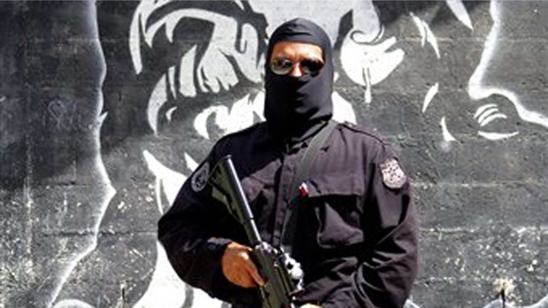 In this April 5, 2016 photo, a masked and armed policeman patrols a gang controlled neighborhood in San Salvador, El Salvador. Hyper-violent gangs declared open-season on police in this Central American nation in response to a government crackdown that began last year. In just three weeks in January, gang members were blamed in the slayings of a cop's father, a soldier's brother, the wives of two police officers and a woman and her son who were relatives of a cop. (AP Photo/Alex Peña)