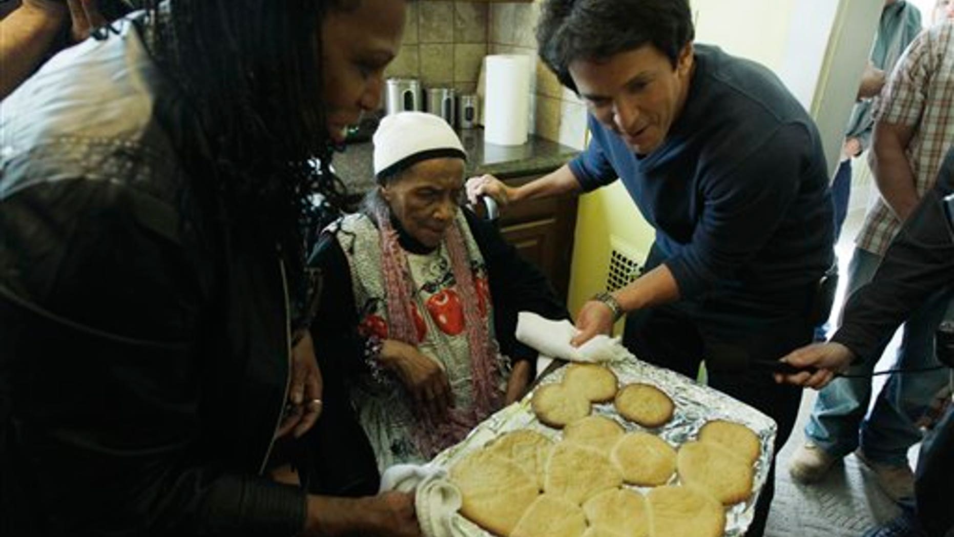 April 4: Detroit Free Press columnist Mitch Albom, right, helps Texana Hollis pull cookies from the oven in her home in Detroit.