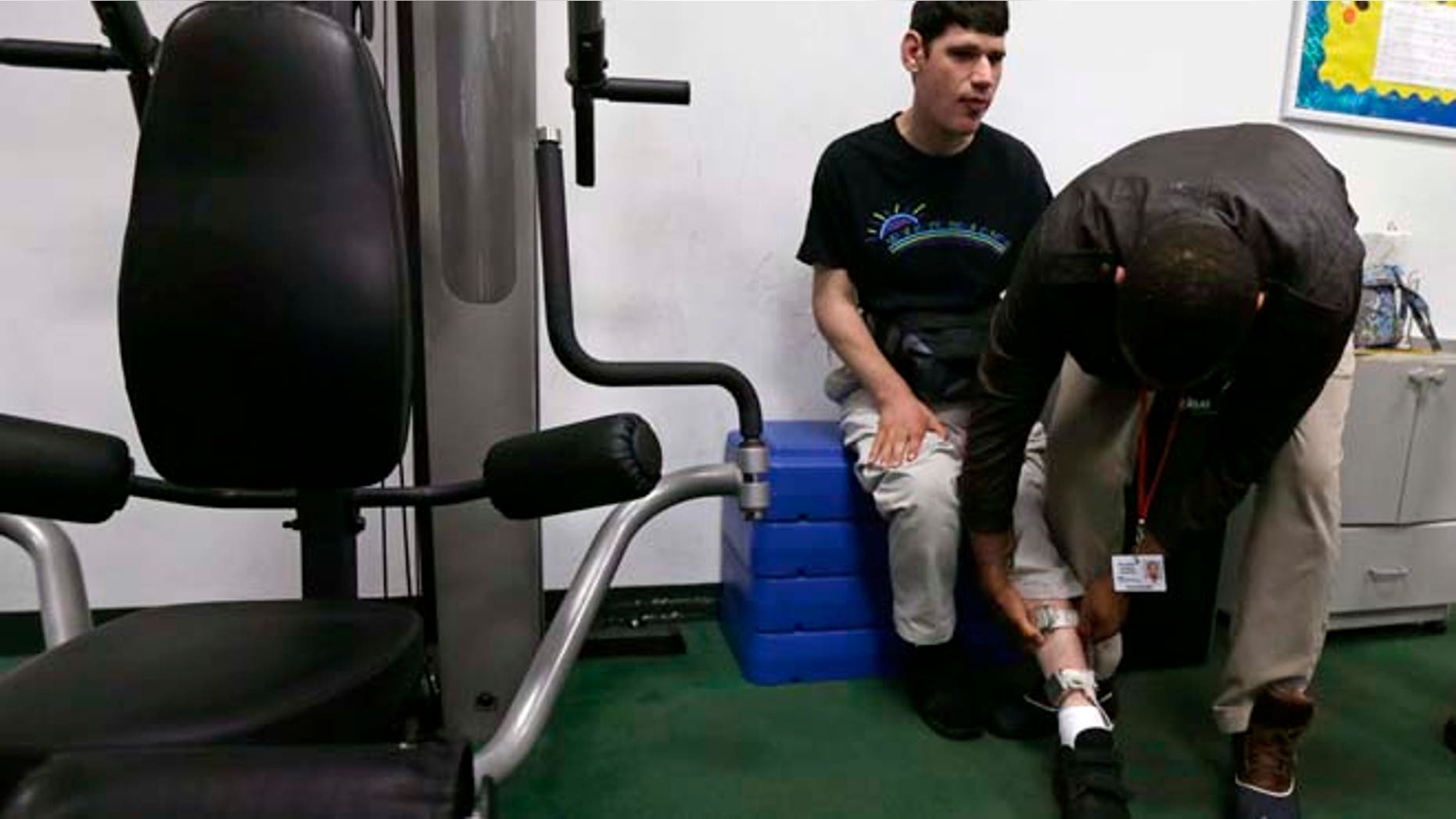 Aug. 13, 2014: In this photo, therapist Joe Andrade checks the ankle strap of a shocking device on student Andrew Goldberg during an exercise program at the Judge Rotenberg Educational Center in Canton, Mass. (AP)