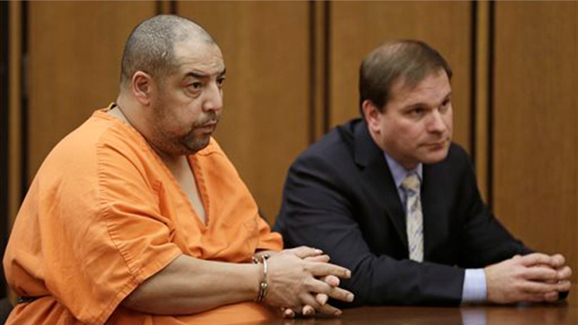 Elias Acevedo, left, looks toward the judge during his pretrial hearing Monday, Dec. 2, 2013, in Cleveland. Acevedo, a convicted sex offender, is charged with two murders and 173 counts of rape. The judge set the trial date for Feb. 24, 2014. Defense attorney Bret Jordan, right, listens. (AP Photo/Tony Dejak)