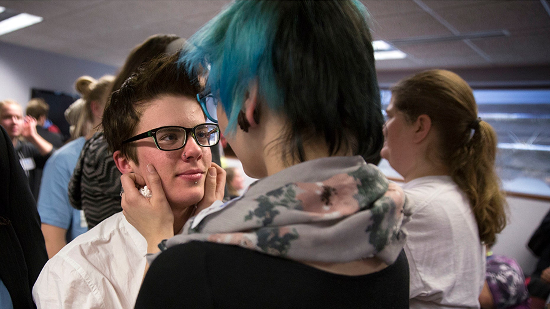 In this Dec. 4, 2014 file photo, Elliott Kunerth, 17, a transgender male high school student hugs his girlfriend, Kelsi Pettit, 17, after the Minnesota State High School League board voted to pass the Model Gender Identity Participation in MSHSL Activities Policy in Brooklyn Park, Minn. (Leila Navidi/Star Tribune via AP)