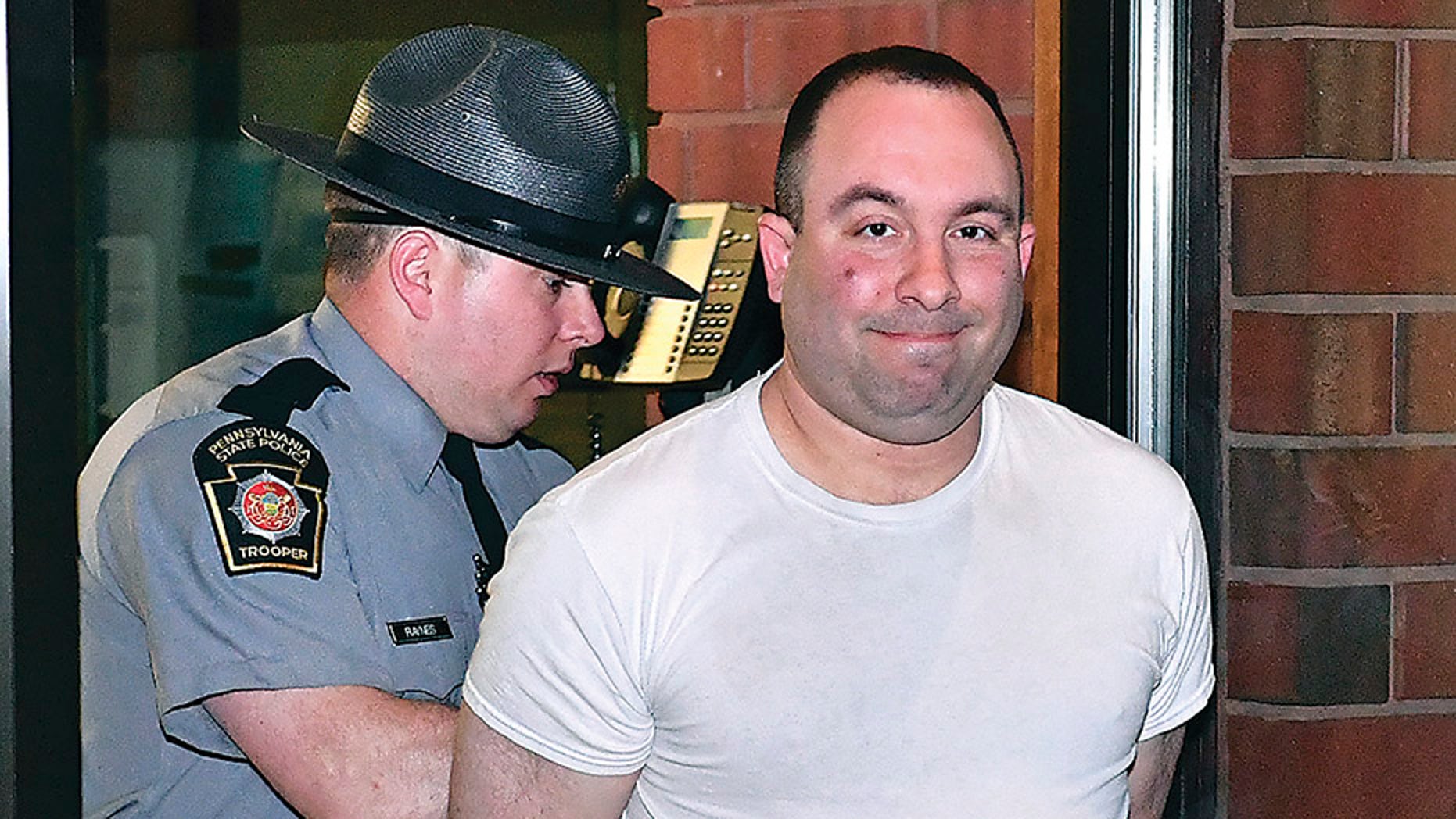 In this April 20, 2018, file photo, Bloomsburg Mayor Eric Bower, right, is escorted out of the State Police barracks in Bloomsburg, Pa., by Trooper Jason Raynes after being video arraigned by District Judge Doug Brewer on misdemeanor charges including criminal solicitation and patronizing prostitutes.