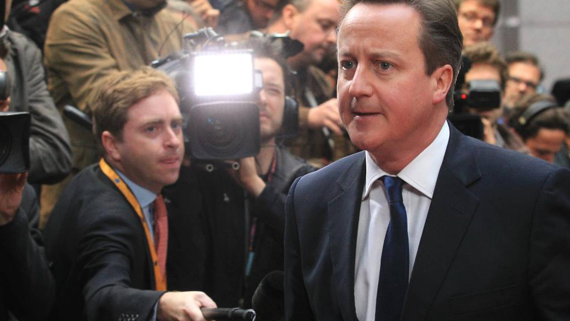 FILE - In this Tuesday, May 27, 2014 file photo, British Prime Minister David Cameron walks past the media upon arrival at the European Council building in Brussels. Many political battles are ugly _ but toss in 28 nations, high unemployment, angry voters and a skeptical Britain and the fight over who will be the European Union’s next chief executive may have downright hideous consequences. Britain’s Prime Minister David Cameron has set himself up for a stinging defeat as his vocal campaign to block the front-runner for the top EU job, former Luxembourg prime minister and longtime Brussels insider Jean-Claude Juncker, fails to gain traction. (AP Photo/Yves Logghe, File)