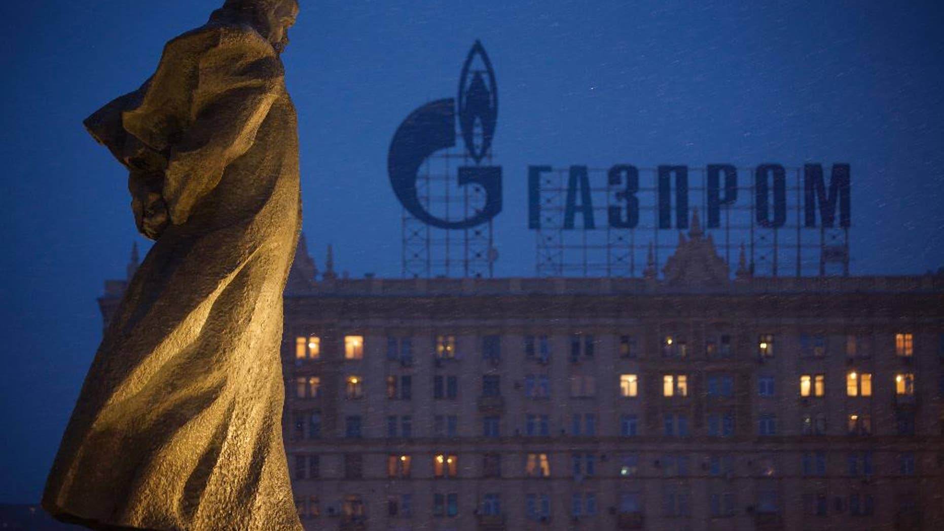FILE - In this Tuesday, March 4, 2014 file photo, a monument to Ukrainian poet and writer Taras Shevchenko is silhouetted against an apartment building with a sign advertising Russia's natural gas giant Gazprom, in Moscow, Russia. Poland has resumed deliveries of gas to Ukraine that it had halted after its own supplies from Russia dropped this week, the state pipeline operator said Friday, Sept. 12, 2014. The statement by Gaz-System S.A. suggests gas flows from Russian supplier Gazprom are once again meeting Poland's daily demand. State gas company, PGNiG, said that on Thursday it still registered some deficit compared to the ordered amount, but that the shortfall was lower than on Wednesday, when supplies were 45 percent short of demand. The spat between Poland and Russia came amid concerns that Moscow is ready to use its energy exports as a political weapon over the crisis in Ukraine."We do not treat the situation as a crisis," Zawisza said. "It is just one incident." (AP Photo/Alexander Zemlianichenko, file)