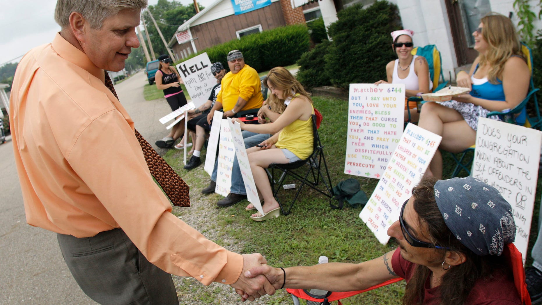 FILE: Pastor Bill Dunfee, left, of New Beginnings Ministries Church, greets supporters of The Fox Hole strip club as they protest against his church in Warsaw, Ohio.
