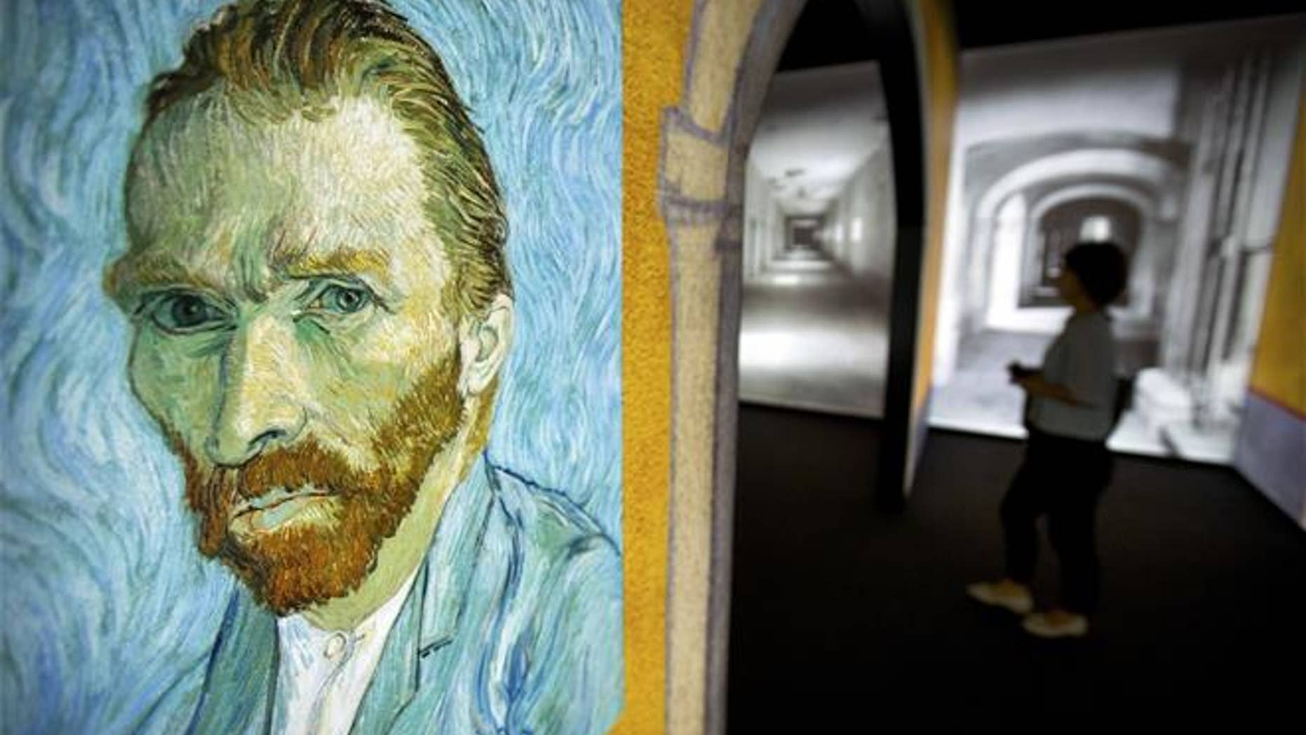 A visitor walks past an image of Van Gogh's "Self-Portrait" during a press event for the world premiere of the "Meet Vincent Van Gogh" exhibit in Beijing on June 15, 2016.