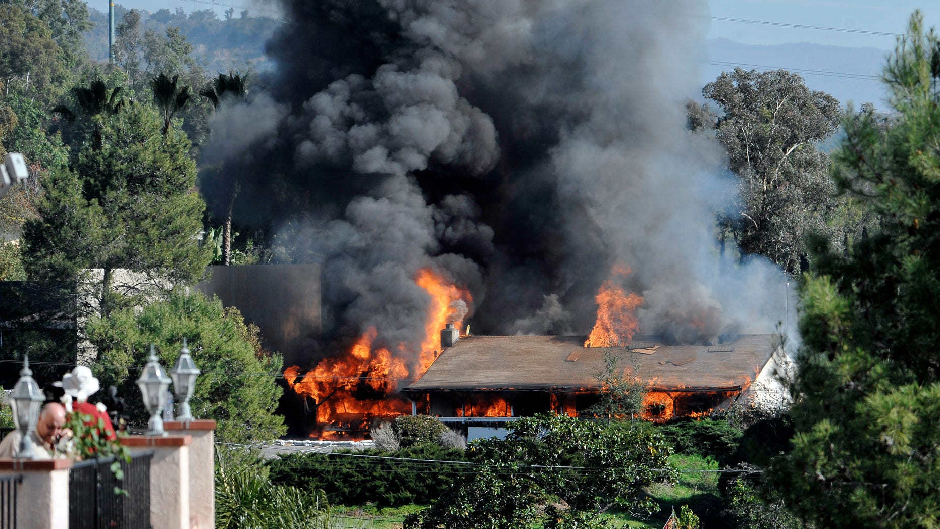 Dec. 9: Neighbors look on as a house burns during a controlled burn in Escondido, Calif., where authorities recently found the largest supply of homemade explosives in a single location in the United States.