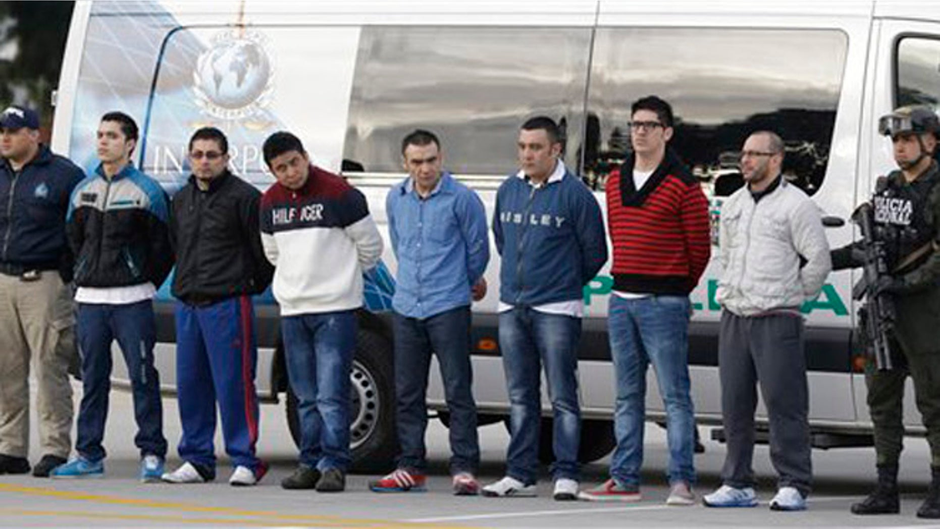 Police flank seven men accused of murdering a Drug Enforcement Administration agent, during a media presentation at the counter-narcotics base in Bogota, Colombia, Tuesday, July 1, 2014, prior to their extradition to the United States. The men are accused of killing Special Agent James "Terry" Watson in an apparent robbery attempt the night of June 20, 2013. (AP Photo/Fernando Vergara)