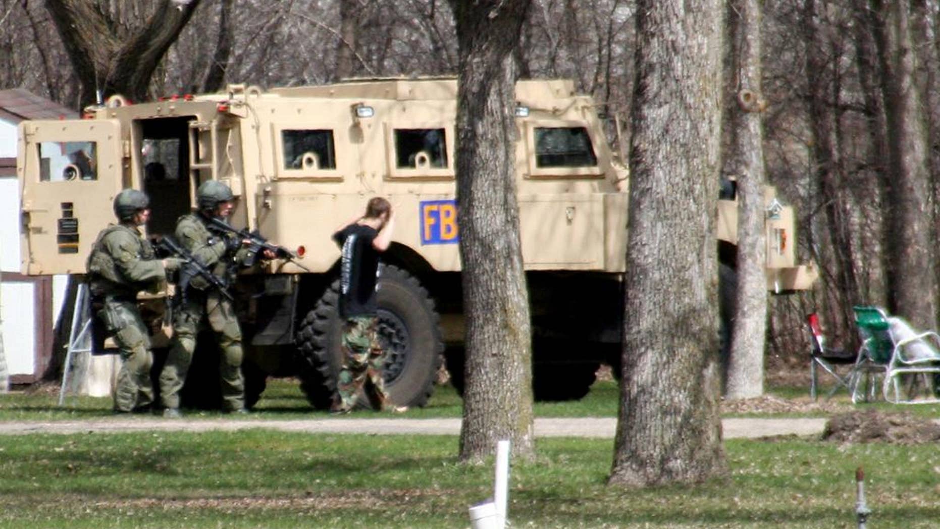 FILE - This May 3, 2013, photo provided by Jeremy Jones shows authorities with Buford Rogers, right, who belongs to a tiny local militia, during a raid on a mobile home in Montevideo, Minn. Rogers, 25, is scheduled to be sentenced Monday, April 28, 2011 after pleading guilty to one count of possessing a firearm illegally and one count of possessing an unregistered destructive device, namely "two black powder and nail devices," which he admitted he made himself. Prosecutors are seeking more than five years in prison, arguing that Rogers poses a threat to public safety, noting the items were designed solely to injure people. (AP Photo/Montevideo American-News, Jeremy Jones, File) MANDATORY CREDIT