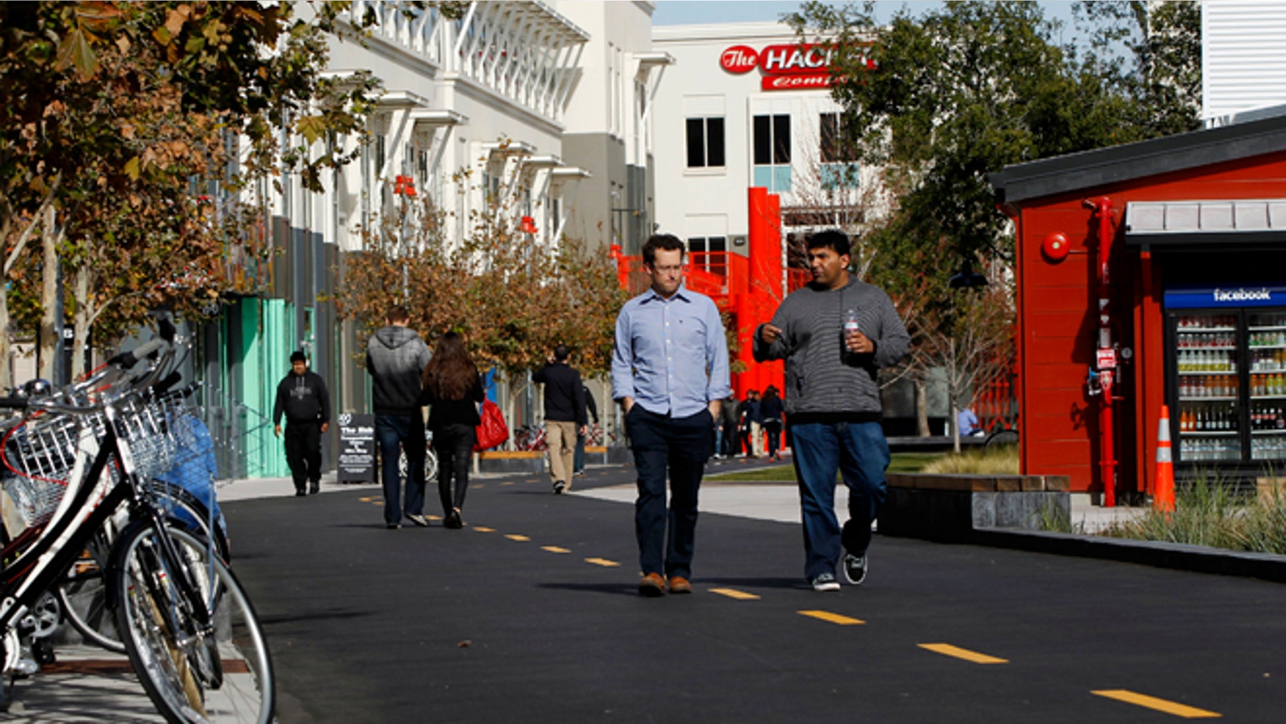 FILE: Employees walk along a walking and bicycle path at the Facebook headquarters in Menlo Park. The Internet giant said it would pay the salary of a police officer in the area.