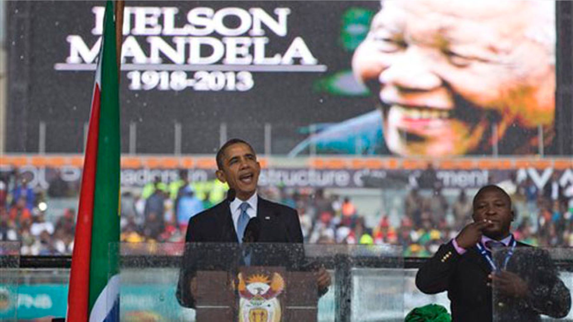 President Barack Obama delivers his speech next to a sign language interpreter during a memorial service at FNB Stadium in honor of Nelson Mandela on Tuesday, Dec. 10, 2013 in Soweto, near Johannesburg.