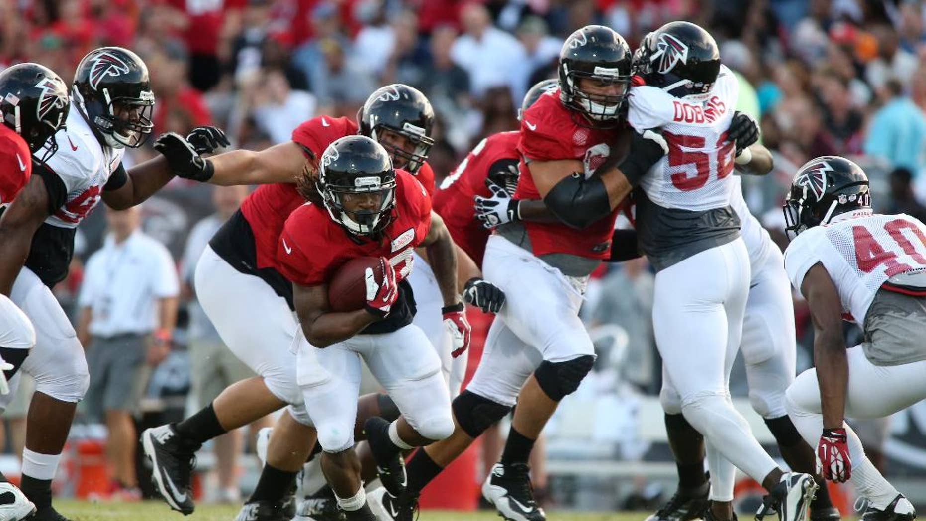 Atlanta Falcons running back Devonta Freeman (33) carries the ball during Friday Night Lights, at Archer High School on Friday, Aug. 1, 2014, in Lawrenceville, Ga. The Falcons continued their tradition of staging a practice at an area high school each year. (AP Photo/Jason Getz)