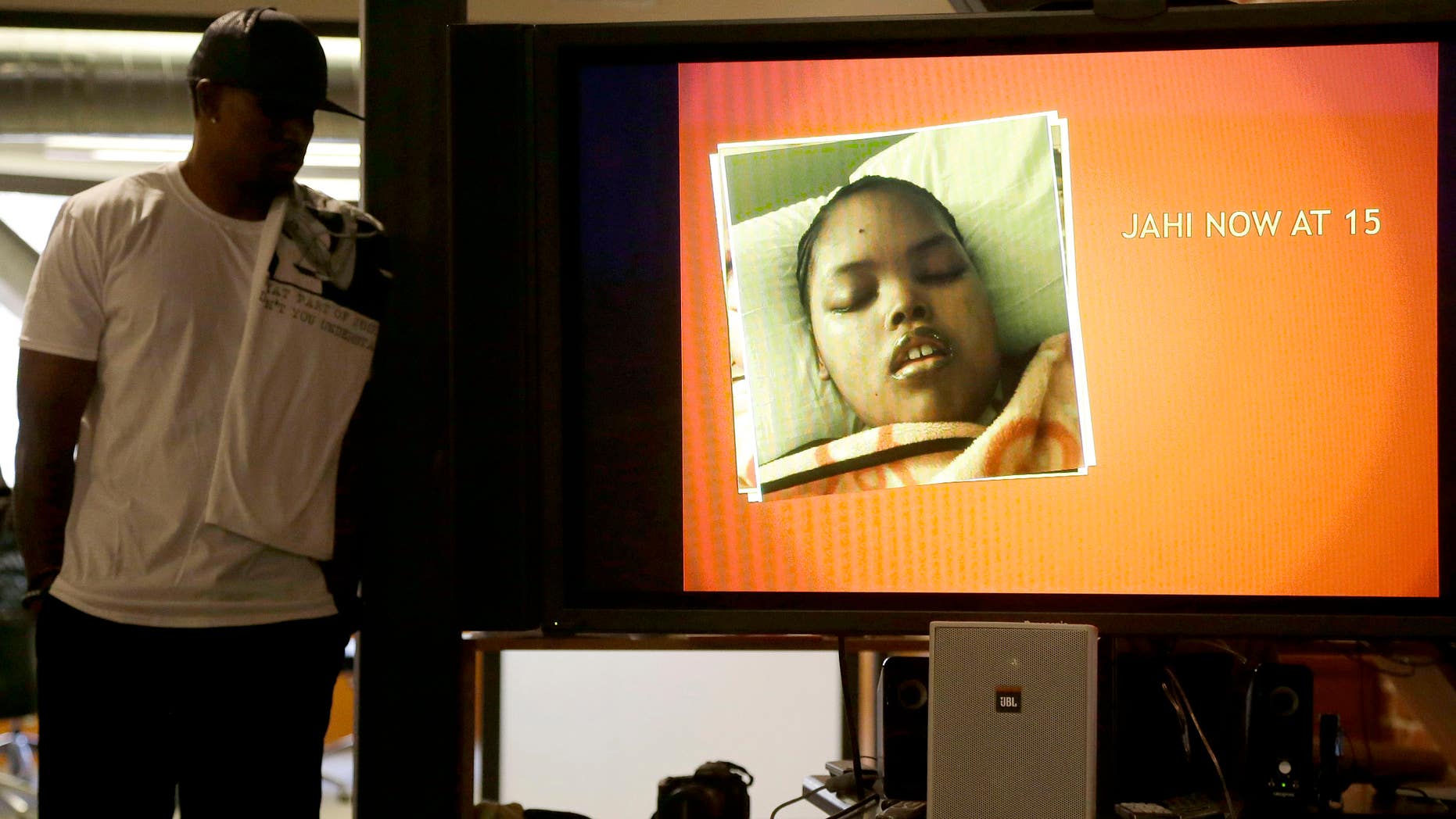 A recent photo of Jahi McMath on a video screen next to her uncle Timothy Whisenton in San Francisco, Wednesday, Dec. 23, 2015.