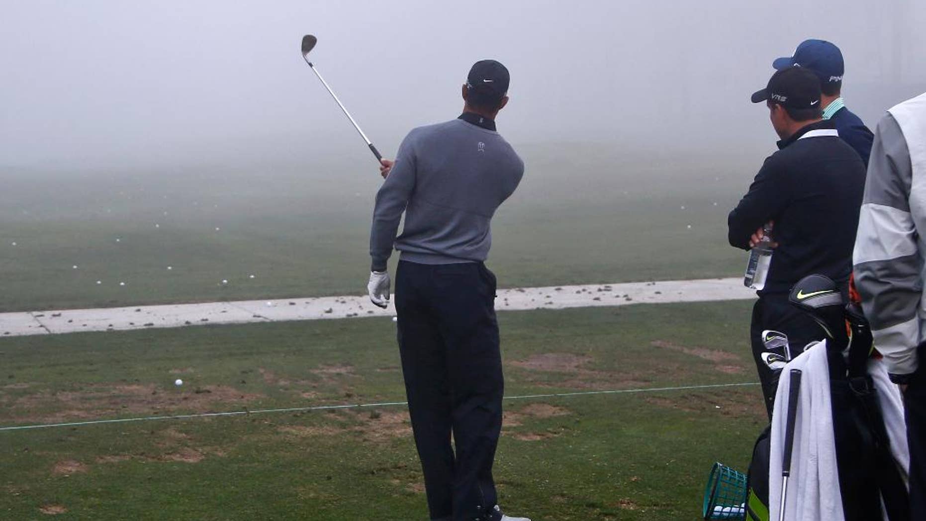 Tiger Woods hits one-handed pitch shots as his coach Chris Como, right, watches during a fog delay prior to the pro-am at the Framers Insurance Open golf tournament at Torrey Pines, Wednesday, Feb. 4, 2015, in San Diego. (AP Photo/Lenny Ignelzi)