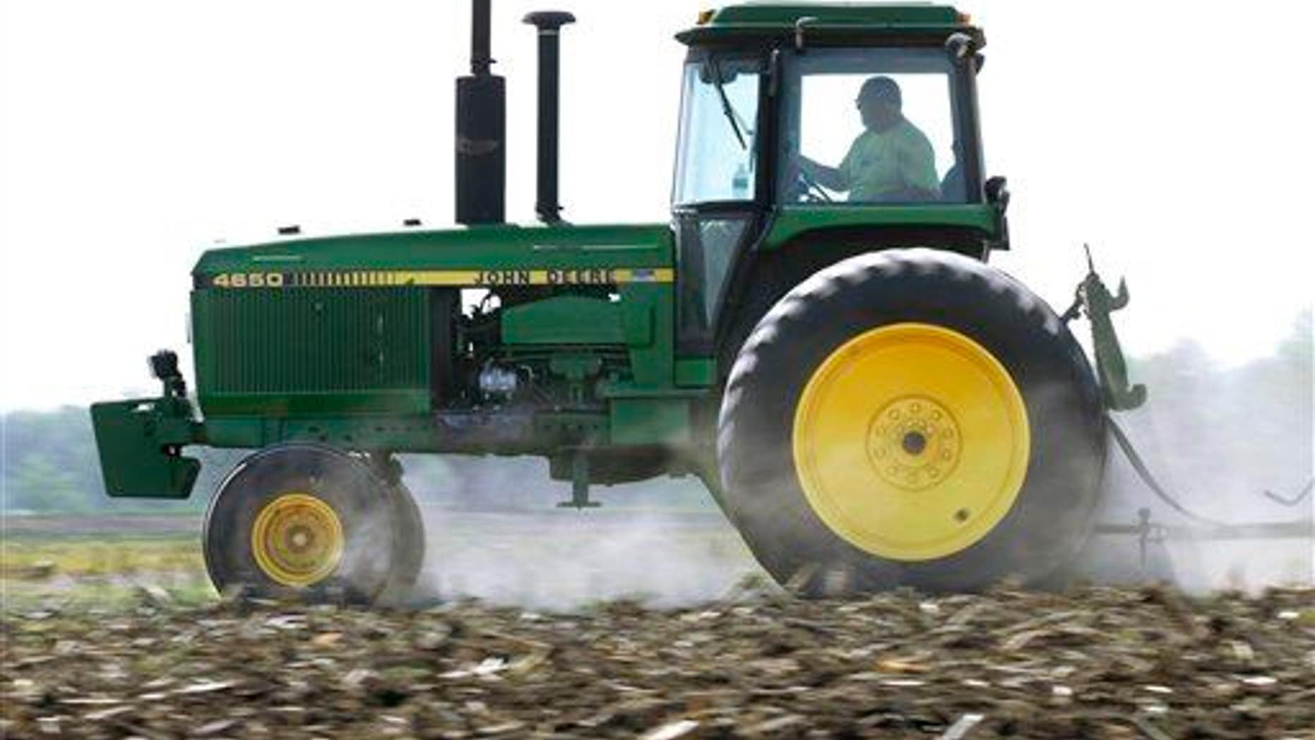 In this April 2, 2012 photo, Derek Long uses a John Deere tractor in preparation for planting corn in Loami, Ill. A slowing global economy and the effects of a prolonged U.S. drought caught up to Deere & Co. as its net income rose 11% but fell well short of Wall Street's expectations.