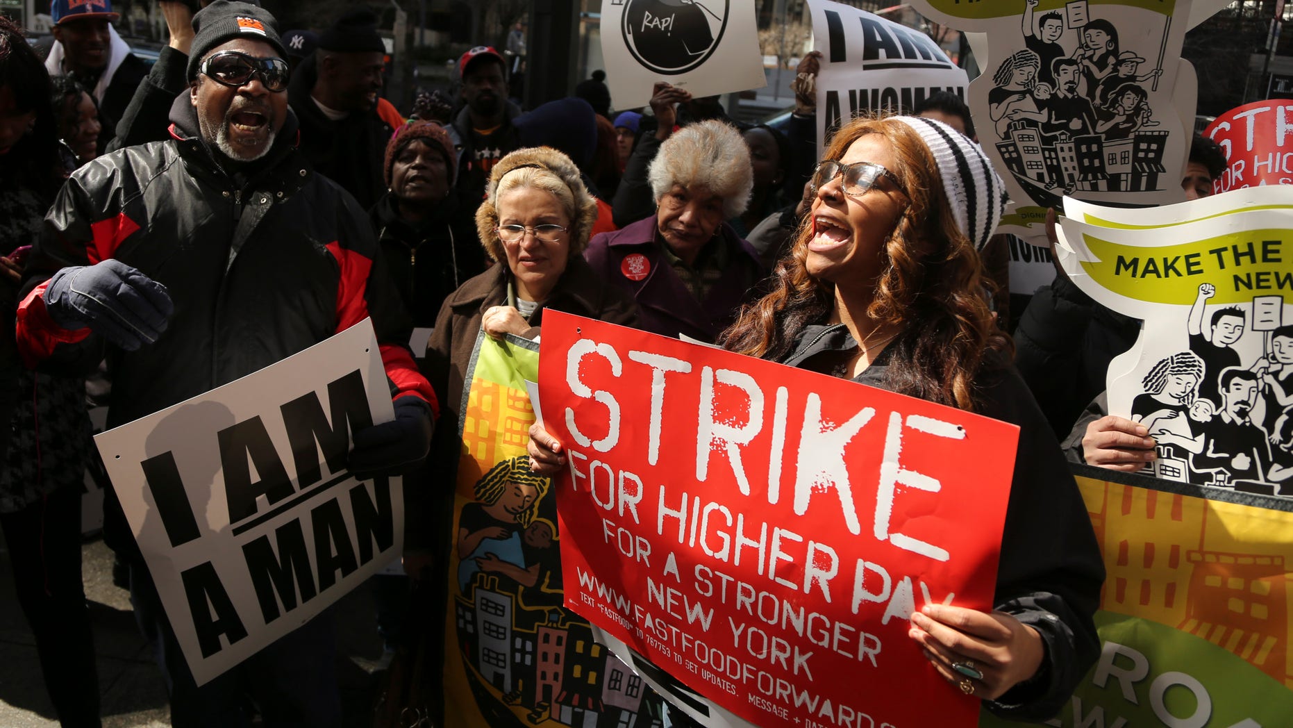 April 4, 2013: Demonstrators holds a sign and chant slogans outside of a Wendy's fast food restaurant in New York. New York City fast food workers plan a second job action day to press for higher wages.