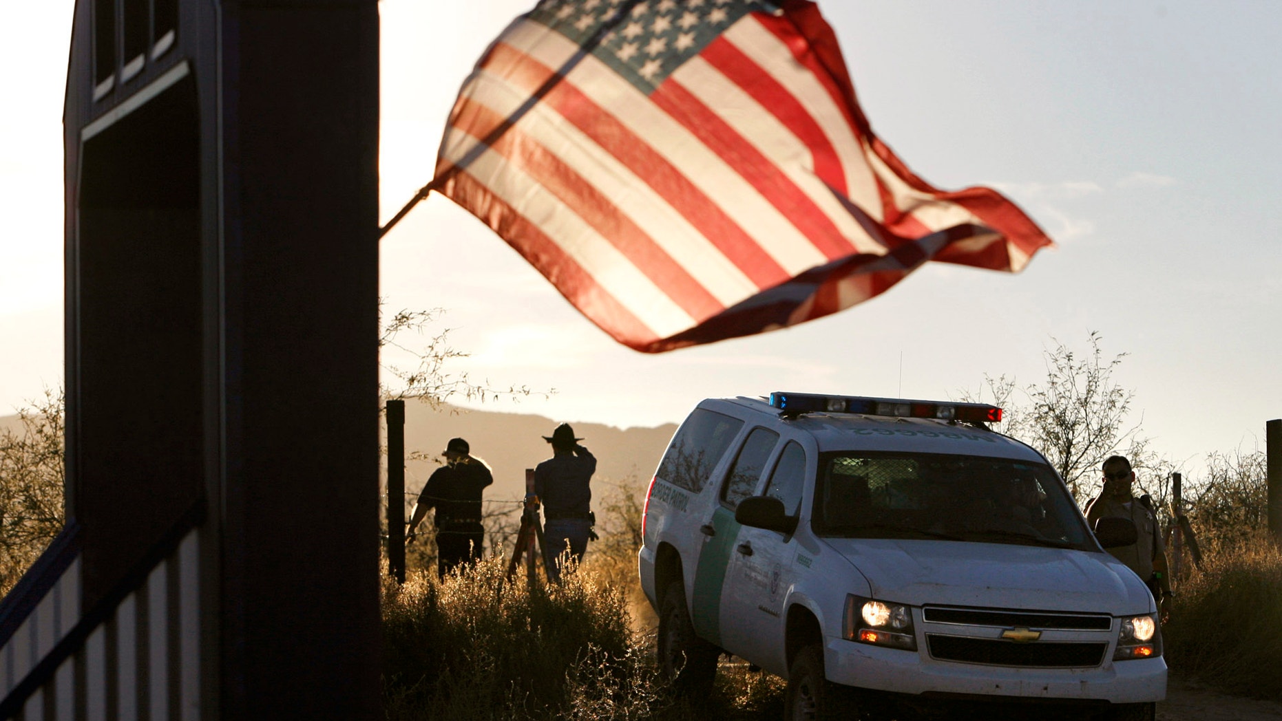 FILE - In this Dec. 15, 2010, file photo, an American flag on a nearby resident's home waves in the breeze near a U.S. Border Patrol truck blocking the road leading to a search area near where agent Brian Terry, 40, was killed northwest of Nogales, Ariz. Two men charged with murder in the death of agent Terry that revealed the bungled gun-smuggling investigation known as Fast and Furious go on trial Wednesday, Sept. 23, 2015. The men were charged in the killing of agent Terry during the Fast and Furious operation in which federal agents allowed criminals to buy guns with the intention of tracking them. Instead, agents from the Bureau of Alcohol, Tobacco, Firearms and Explosives lost track of 1,400 of the 2,000 guns involved in the sting operation, including two weapons found at the scene of Terry's killing. (Greg Bryan/Arizona Daily Star Via AP, File) MANDATORY CREDIT; GREEN VALLEY NEWS OUT;